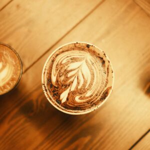Close-up aerial shot of three cups of coffee with intricate latte art on wooden table.