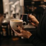 Close-up of a barista making coffee, highlighting latte art and cozy café atmosphere.