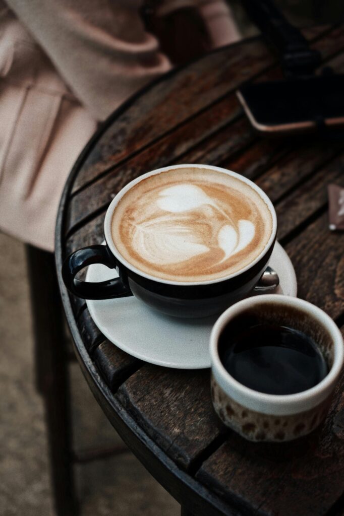 Artfully crafted latte and black coffee on rustic table, perfect for a cozy cafe ambiance.